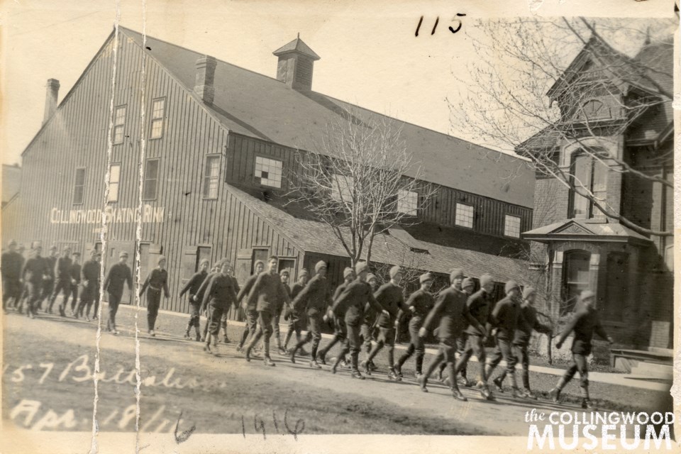 A group of more than thirty recruits for Collingwood’s 157th Battalion march north towards Second Street in front of Collingwood’s original skating rink and the home of William and Sarah Hughes. 
Huron Institute 115; Collingwood Museum Collection X969.730.1. Photo contributed by Collingwood Museum.
