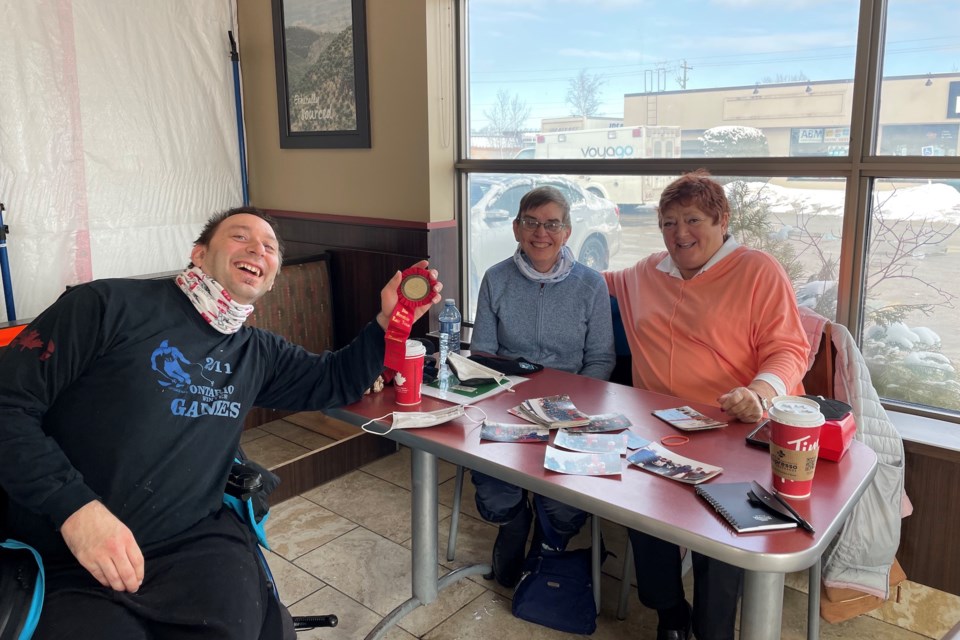 Rob Roest, Laurie Roest and Patty Federer looking at photos and reminiscing about the 1997 games.