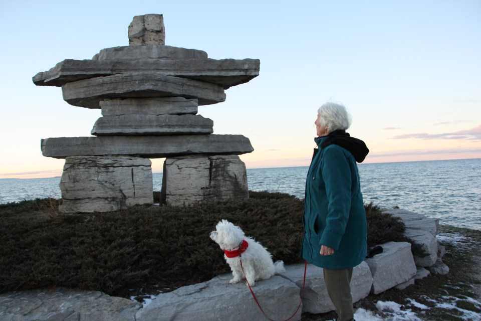 Betty Wallwork and her dog Lanei look at the Inukshuk at Sunset Point, one of their favourite places to walk in Collingwood. Wallwork is concerned the erosion along the shoreline will eventually mean the end of Sunset Point. Erika Engel/CollingwoodToday
