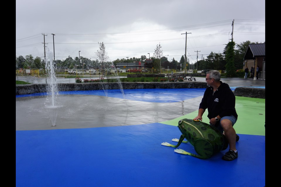 Dean Collver, the town's director of parks, recreation and culture, presses a frog-shaped water activator at Awen' Waterplay on Aug. 18, 2023.