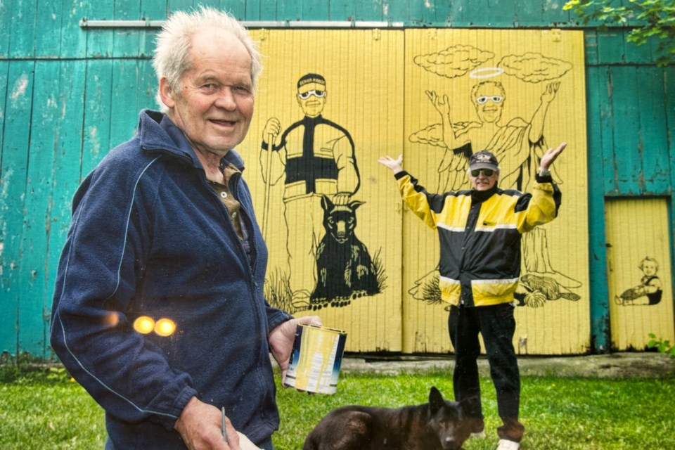 John Haines with some of his barn-door murals at Bob King's farm in Maxwell. Bob King is on the right, Haines is on the left. 