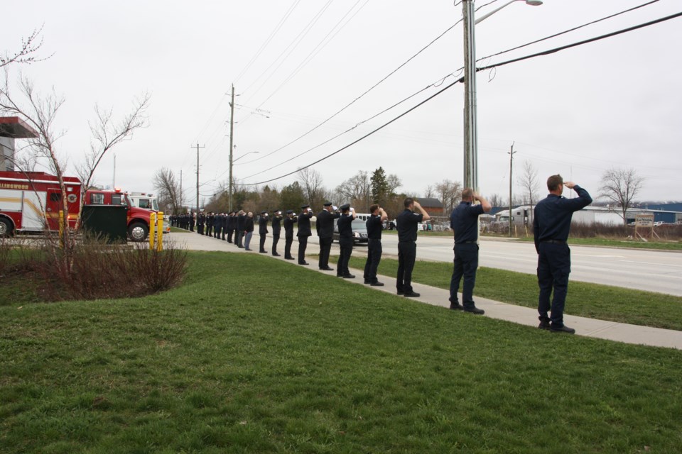 Active and retired members of the Collingwood Fire Department salute as a hearse drives by. They were sending off Retired Fire Chief Francis Maguire, who died on April 29. Erika Engel/CollingwoodToday