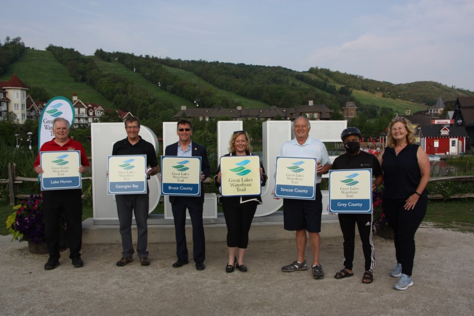 Local and provincial officials show off the new signs for the latest stretch of the Great Lakes Waterfront Trail. 