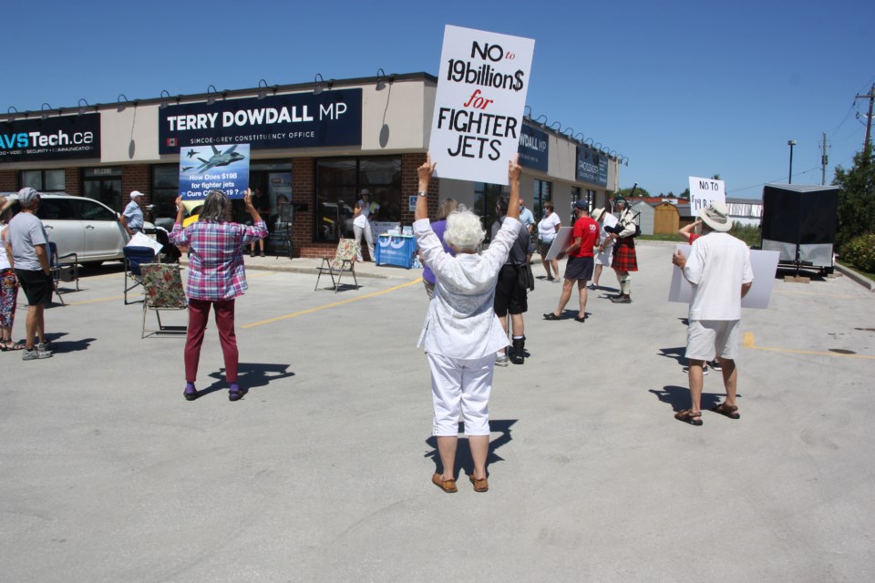 22 people protested outside of MP Terry Dowdall's office calling for the cancellation of the planned spending of $19 billion for new fighter jets. Erika Engel/CollingwoodToday