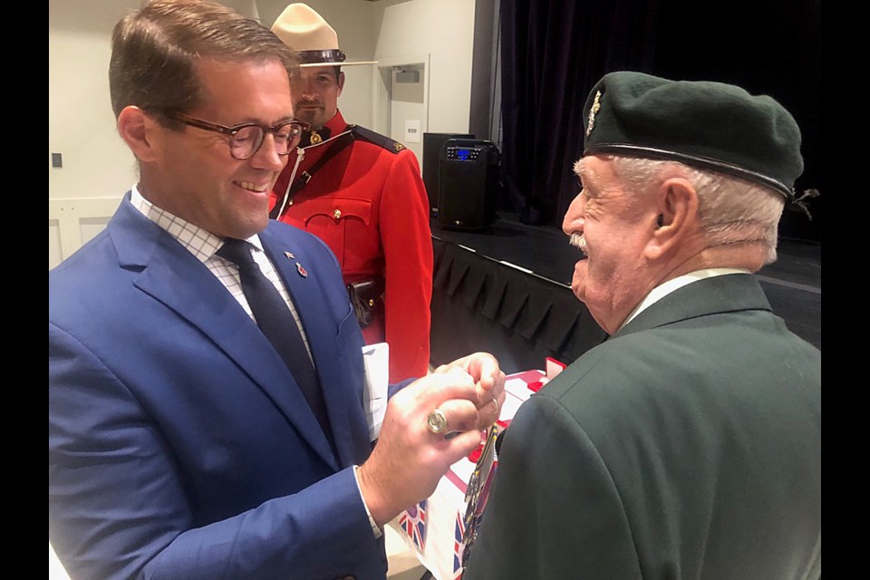 MP Bob Zimmer pins 1952-54 Korean War veteran David Ward, while DC RCMP Cst. D. Dan Gilroyed looks on.