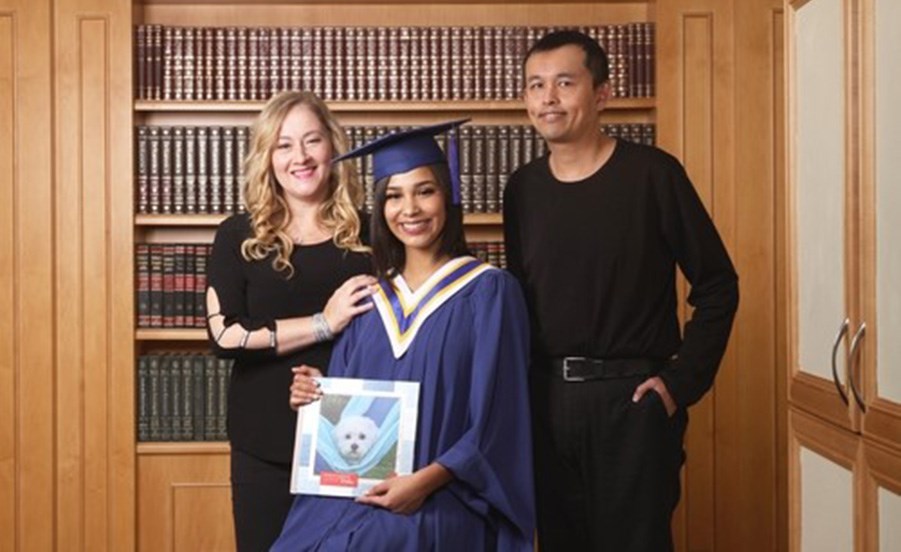 Beddie Luminaries scholarship winner Nyah Gentry with her mom Stacey and Roger Au while holding a book with a photo of her beloved dog Bella who inspired her to study veterinary medicine. 