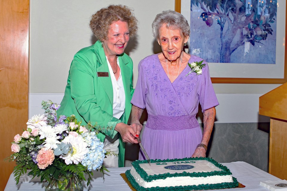 Anne Sanders and Pat Walton cut a cake to mark the 20th anniversary celebration at Augustine House on Thursday, Aug. 3.