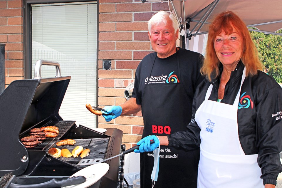 Deltassist held its Christmas in July fundraiser on Sunday, July 30 at its offices in North Delta. The day included a barbecue, car wash and an appearence from the BC Lions cheerleaders. Pictured are: Len Morro and Elaine Greggain on the barbecue.