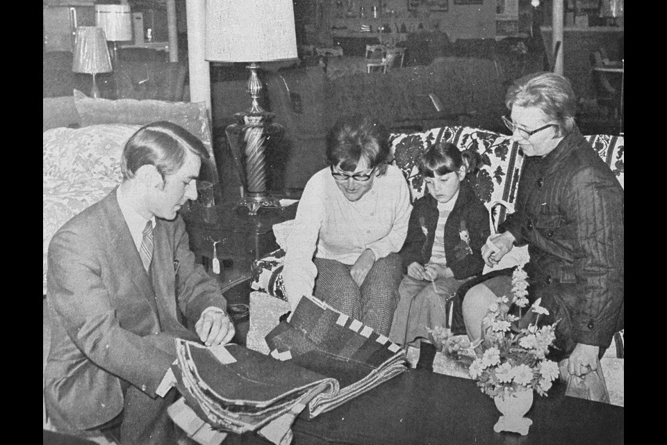 Tom Hobman, manager of the new Comfort Home Furnishings, shows merchandise to customers Doreen Lowery, daughter Jennifer and Corrinne Johnson.