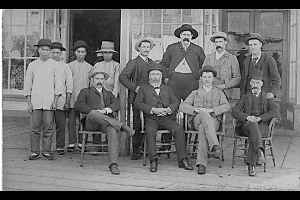 Thomas McNeely (middle) seated in front of his general store which sold a wide selection of merchandise.