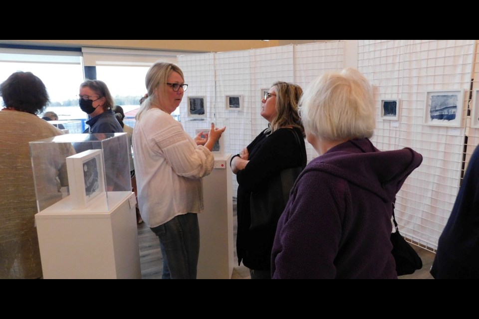 Artist Shar Hamlin talks with some of those attending the open house of her Timber Village Museum exhibit of fabric art.