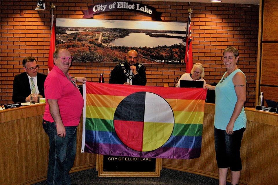 Pride Two Spirit Flag held by Douglas Elliott and Chantal Vaillancourt in Elliot Lake Council Chamber. Brent Sleightholm for ElliotLakeToday