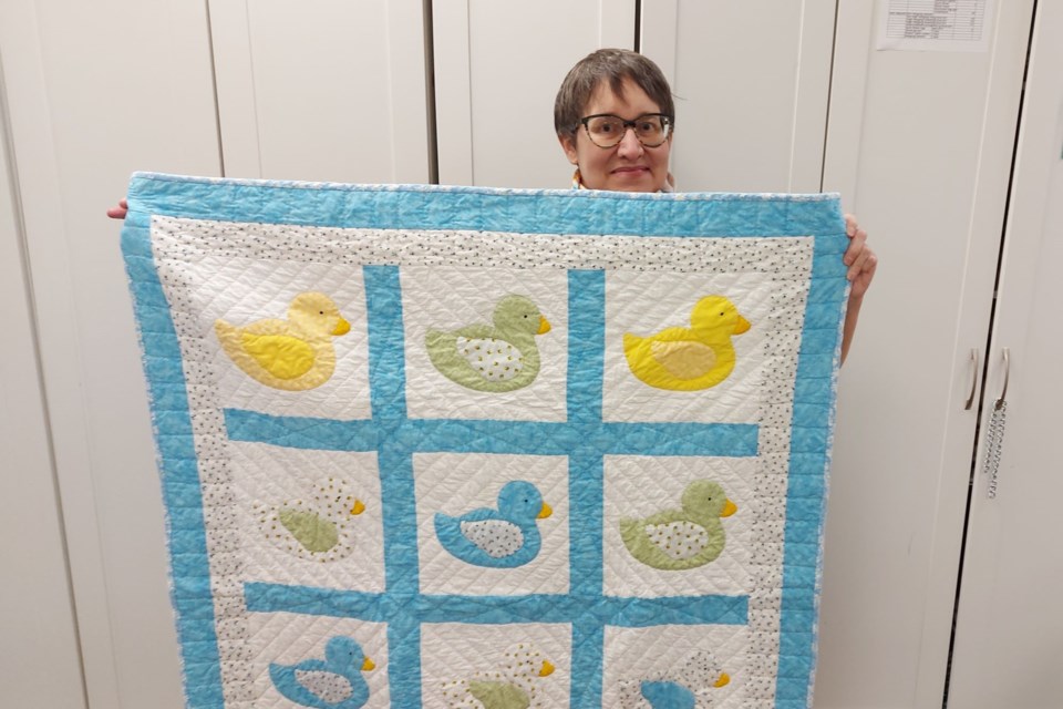 The guild has prepared quilts such as this for the first baby born in 2024, held by Elliot Lake Quilt Guild president Monique Fourcaudot.