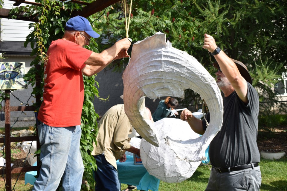 Dick Harmon, left, and Andrew Pipe jointly hang one of the sculptures so volunteers can tackle them from both sides. 