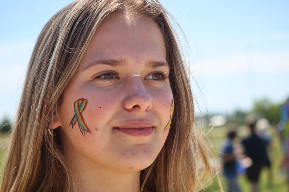 A volunteer at the event has their face painted with the cancer research logo.
