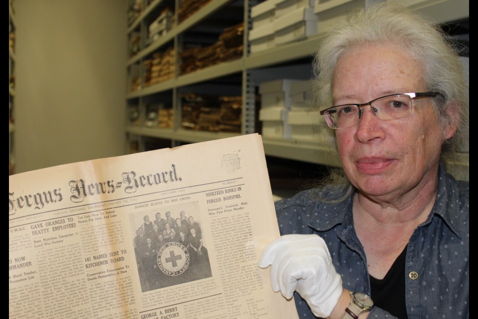 County archivist Karen Wagner holds up a copy of the Fergus News-Record from January 1943.