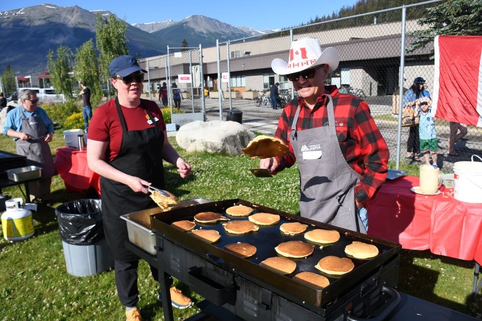 Jasper Mayor Richard Ireland, right, flips flapjacks during the pancake breakfast in Commemoration Park in Jasper, Alta. on Tuesday, July 1, 2025.