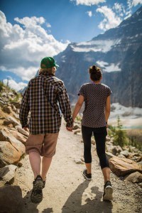 A young couple hold hands as they hike up the paved path at Mount Edith Cavell