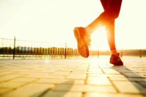 Runner feet running on road closeup on shoe. woman fitness sunrise jog workout welness concept.