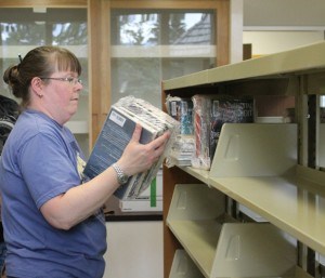 Angie Thom, director of library services, places some of the first books on the library's new shelves, June 8. Photo - K. Byrne. 