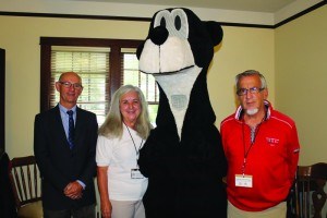 Mayor Richard Ireland (left) and Communities in Bloom judges Evelyn Alemanni and Ga矇tan Desch礙nes pose with Jasper the Bear on July 14. The two judges spent the day touring the town, judging the community in several categories. K. Byrne photo