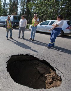 Members of a municipal utilities crew keep an eye on a sink hole that opened up in the road outside the Bottle Depot in Jasper’s industrial park. File photo. 