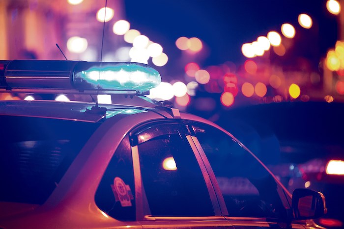 Blue light flasher atop of a police car. City lights on the background.