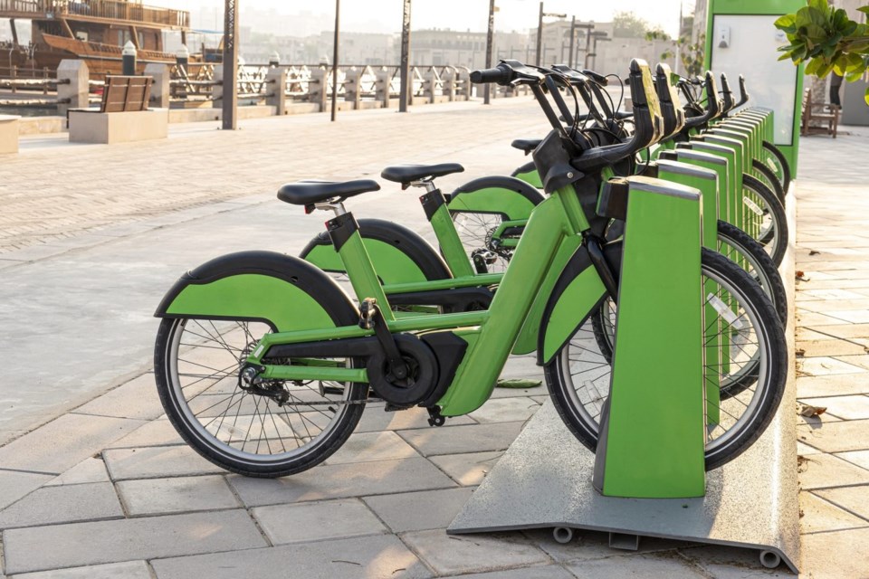 electric bicycles for rent are green in parking lot in the city center on the street. Eco-friendly mode of transport