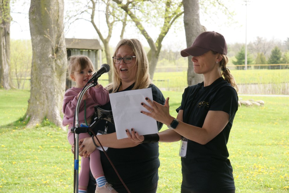 Stephanie Kolaski (with daughter Camryn) shares her story during Flora's Walk in Waterdown as Lotus Counselling owner Elisha Schafer looks on.