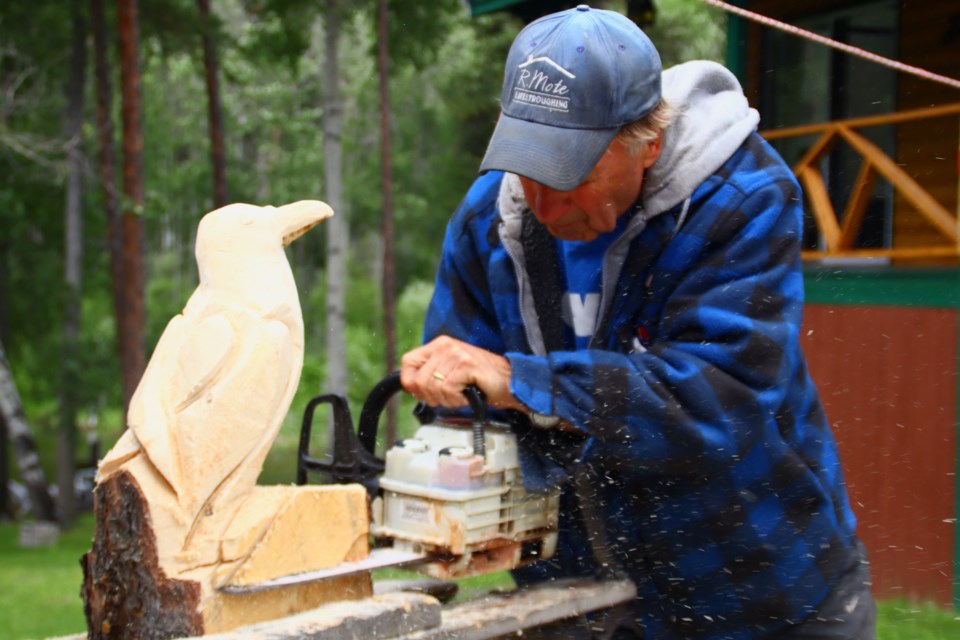 Beaner Deans uses a chainsaw to cut out part of a raven carving. The carver uses other tools to help shape up his creative vision, but his main instrument is a chainsaw.
