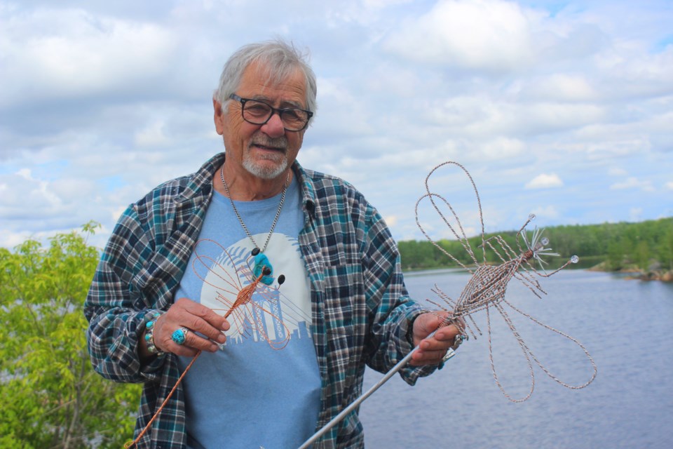 Sid Overby shows off a pair of his creations - dragonfly sculptures made of copper lead wire. Overby finds inspiration in his battles against cancer and a desire to help other people, to whom he often gives the sculptures away.