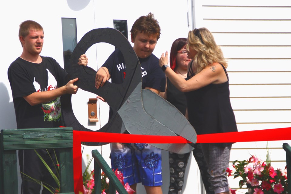 Jared Jebsen and Zavrett Pelletier, oversize pair of scissors in hand, officially cut the ribbon to open Northern Growing Abilities July 23.