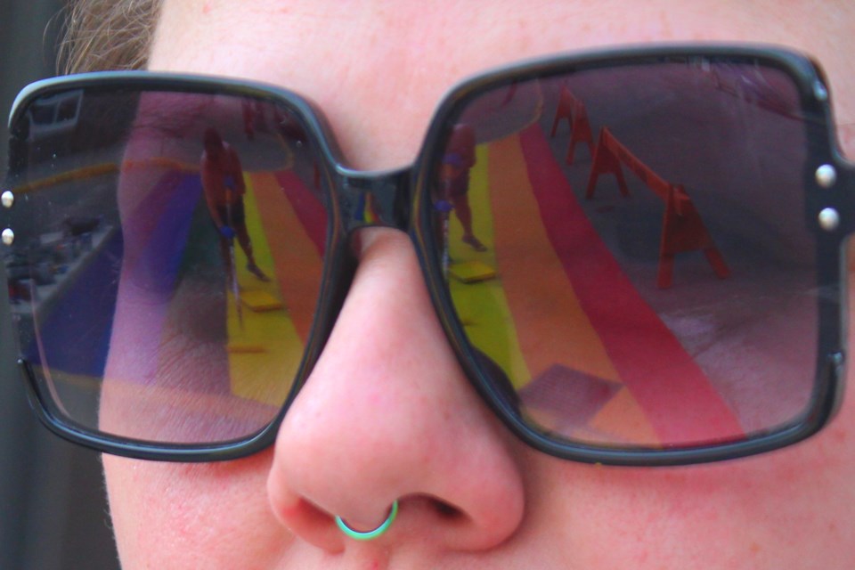 The Flin Flon Pride crosswalk is reflected in Jordana Oulette's sunglasses while it is repainted July 3.