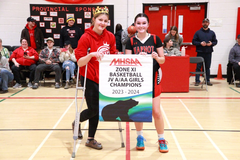 Ariana Bellisle and Taylor Burwash hold up the zone banner the Kweens won during the Zone 11 championship tournament Feb. 24.
