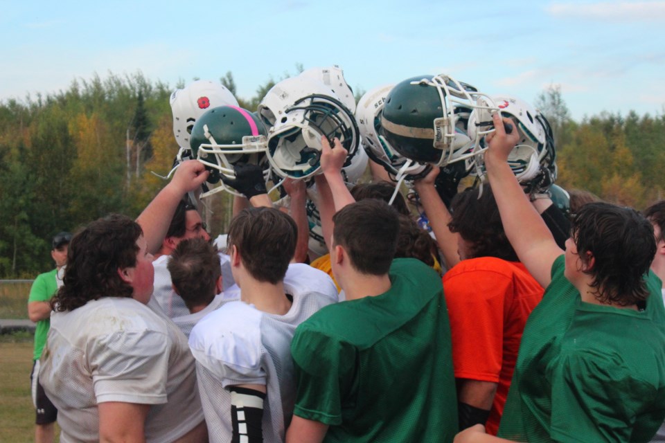 Players hoist their helmets together at the end of practice.