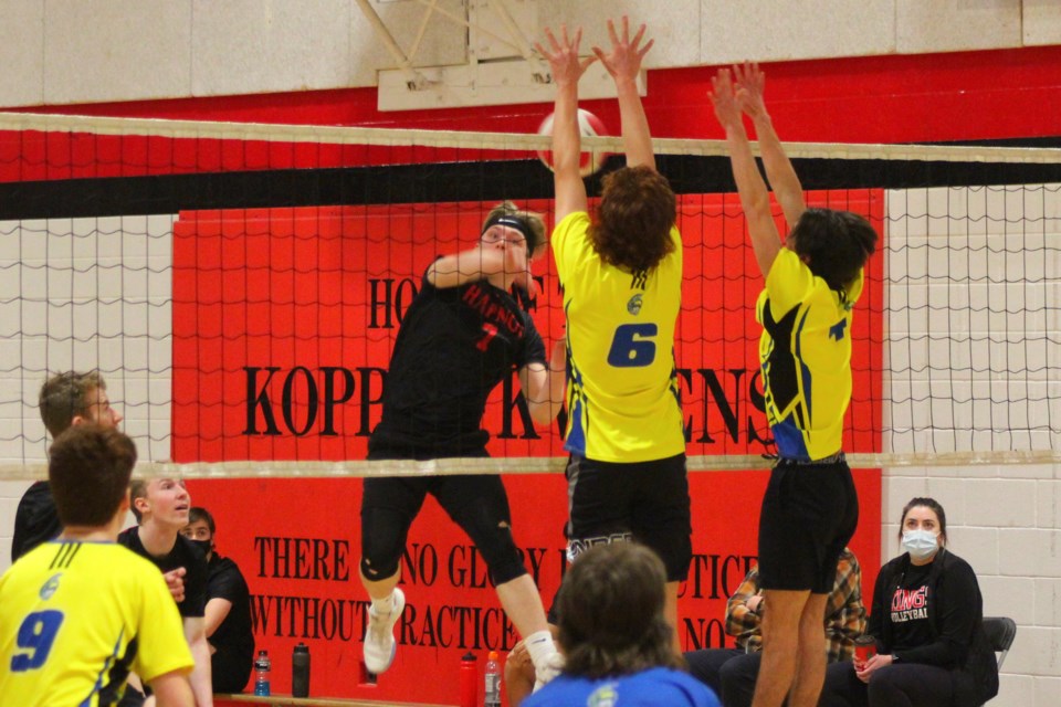 Ethan Patterson blasts a spike at a pair of blockers during a round-robin game against
MBCI.