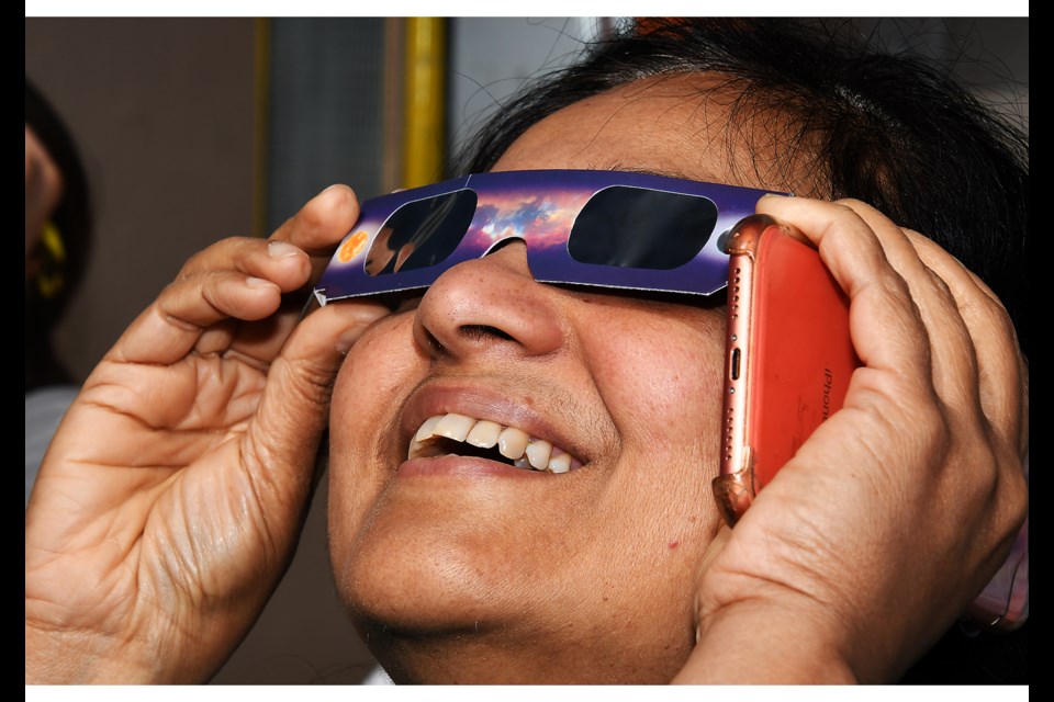 Ajitha Ratnam of Oakton watches the April 8, 2024, solar eclipse at its peak behind protective glasses at Turner Farm Observatory Park in Great Falls.
