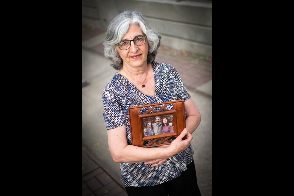 Nahid Mazloum, holds up a portrait of her mother Ezzat Janami Eshraghi, sister, Roya Eshraghi and her father, Enayatollah Eshraghi all of whom were executed in June 1983 in Iran for their belief in the Baha’i faith.