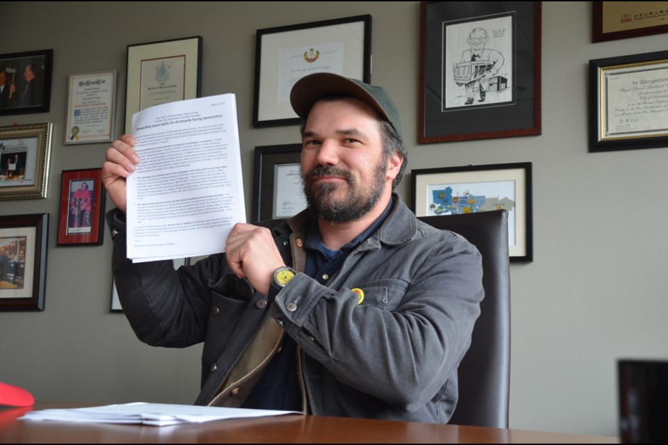 Ivan Drury with the Stop Demovictions campaign sits at Mayor Derek Corrigan's desk on Thursday morning, as part of a three-hour sit-in.