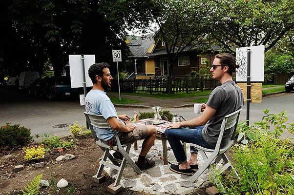 George Rahi (left) and Julien Thomas enjoy a cup of coffee on the traffic calming circle at St. George and 10th Ave.