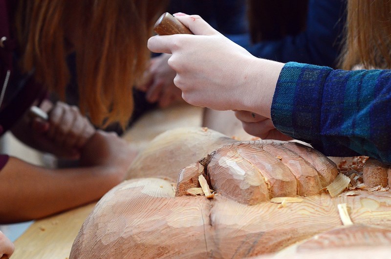 A welcome figure modelled after a traditional Coast Salish house post is texturized by carving knives wielded by Burnaby Central Secondary students.
