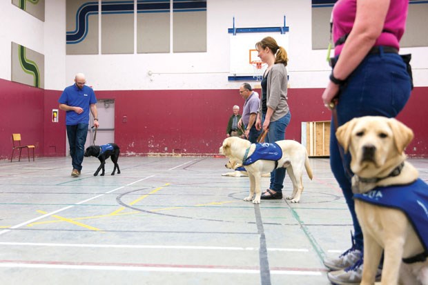 Volunteer puppy trainers and their dogs observe puppy training supervisor Matthias Lenz (left) demonstrate a drill at an obedience class held at Ladner Baptist Church last month.