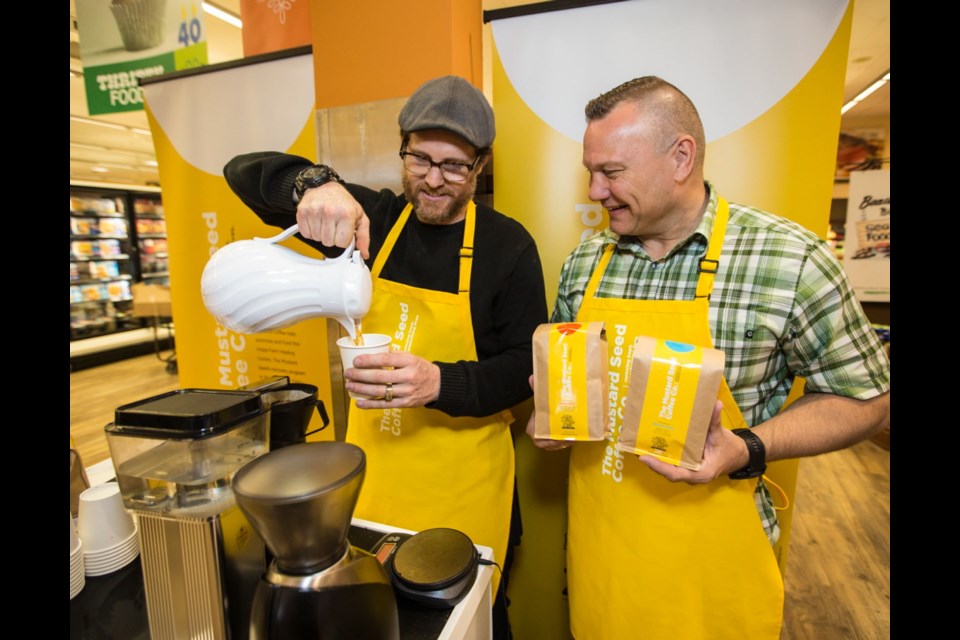 Cody Smith from the Hope Farm Healing Centre Program pours a Mustard Seed coffee with Mustard Seed executive director Bruce Curtiss.