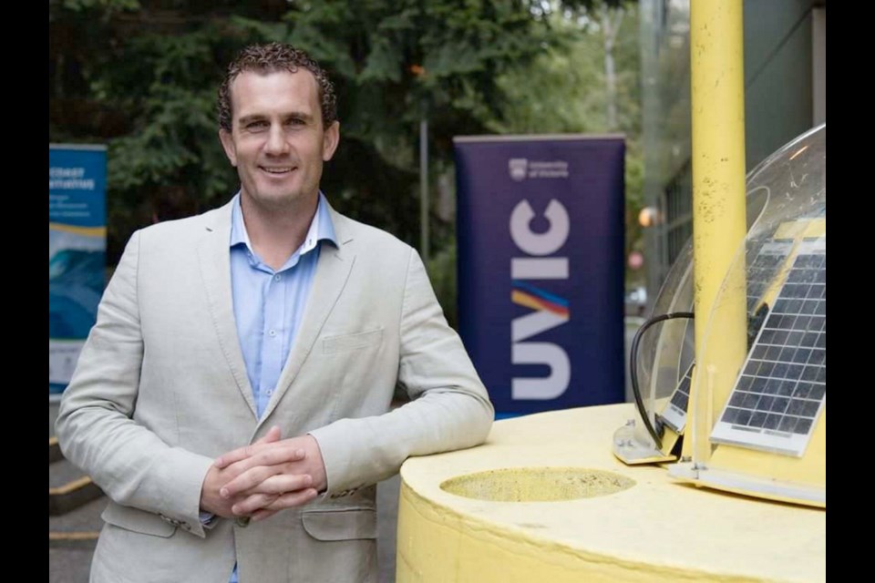Report lead author Bryson Robertson poses with a wave measuring buoy at the University of Victoria.