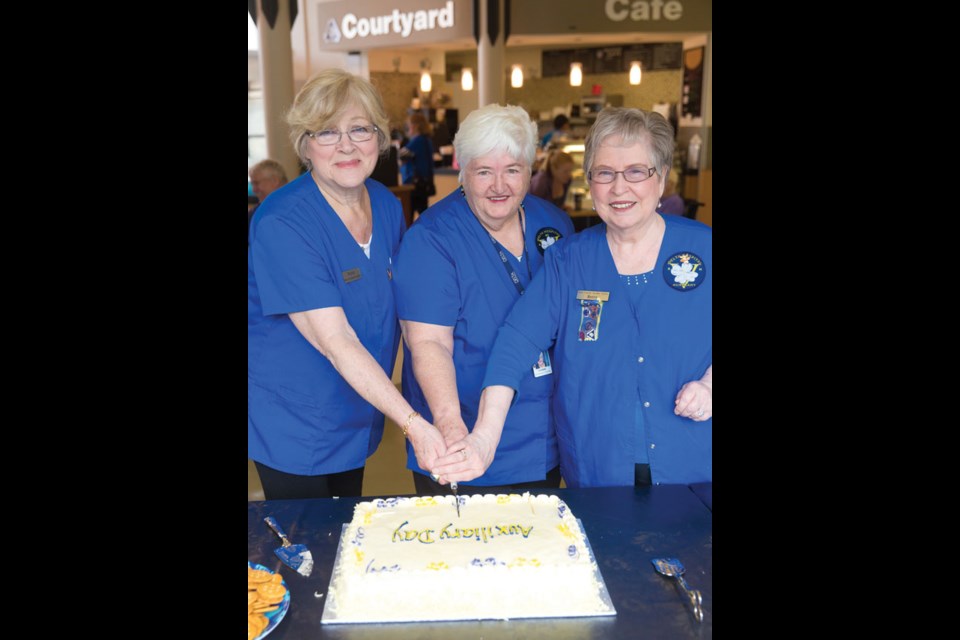 The Delta Hospital Auxiliary celebrated Healthcare Auxiliary Day, a proclamation of the Ministry of Health, during a recent event at Delta Hospital. Delta Hospital Auxiliary president Yvonne Chard (middle) gets help cutting the cake from past presidents Robbie Schultes (left) and Betty Davies.