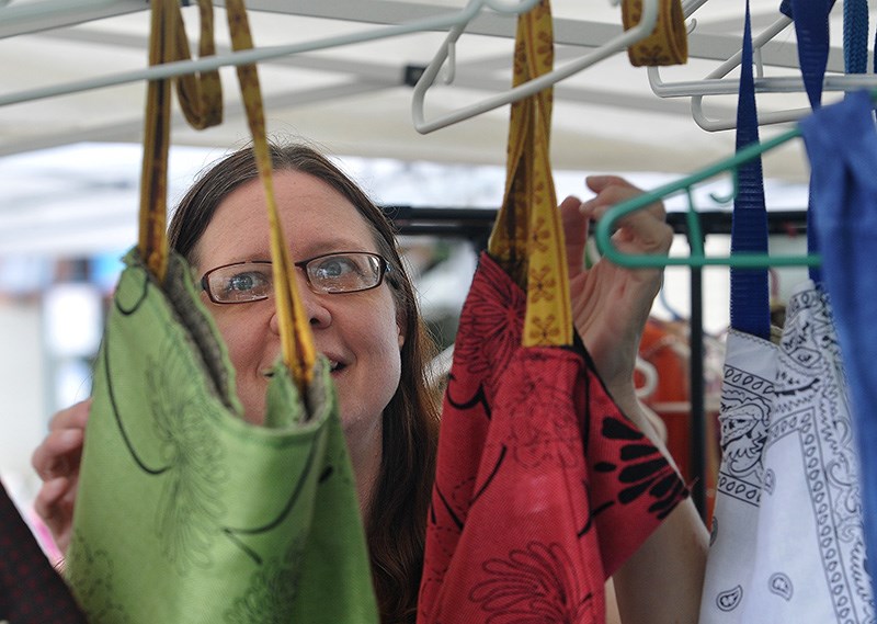 MARIO BARTEL/THE TRI-CITY NEWS
Tabetha Farnell adjusts handbags in one of the artisan booths at the opening day of the PoCo Farmer's Market on Thursday.
