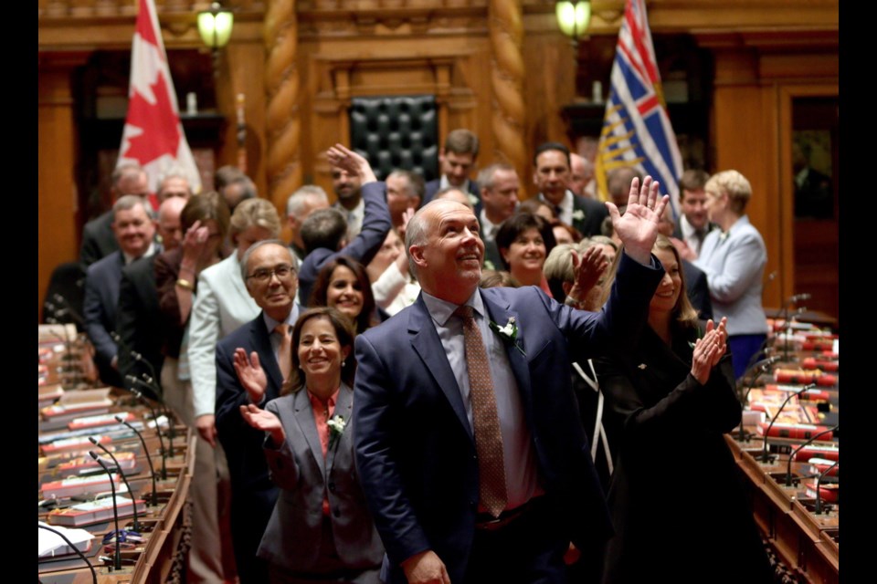 B.C. NDP Leader John Horgan waves to supporters in the legislative gallery following a swearing-in ceremony on Thursday. June 8, 2017