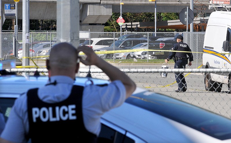 MARIO BARTEL/THE TRI-CITY NEWS A member of the RCMP's Explosive Devices Unit removes a suspicious package from the Coquitlam Centre bus loop as members of the Coquitlam RCMP stand by. The area was closed off for almost an hour.