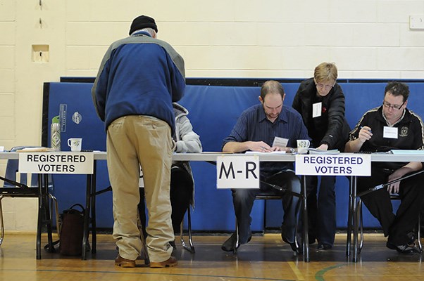 A voter checks his registration at a polling station at Emily Carr elementary school Saturday.