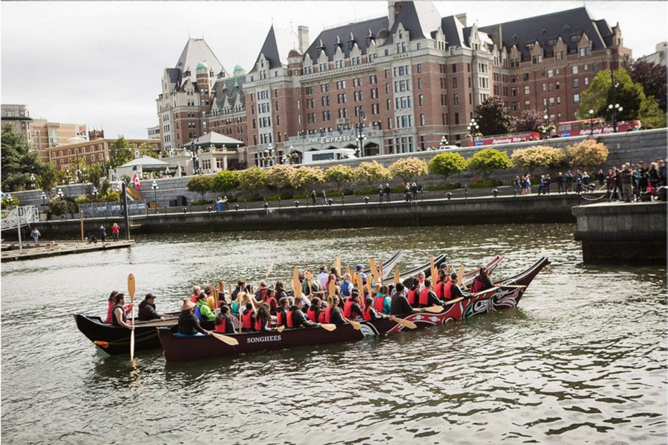 Songhees Nation paddlers pass by the crowds on the Lower Causeway.